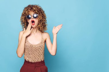 Büyüleyici model güneş gözlüğü mavi arka plan şaşırmış el hareketlerine bak 