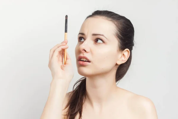 Brunette naked shoulders brush in hands applying cream — Stock Photo, Image