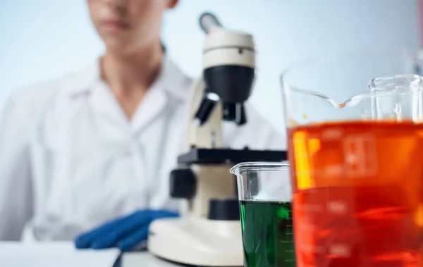 Женщина врач в медицинском платье и микроскоп на столе очки на лицо лабораторные исследования — стоковое фото