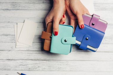 Kadın ellerinde çok renkli kartvizit tutucular ve tahta bir arka planda bir paket beyaz kağıt.