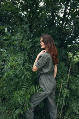 Tulum giymiş bir kadının portresi. Yeşil çalıların yanında. Yan manzara seyahati. 