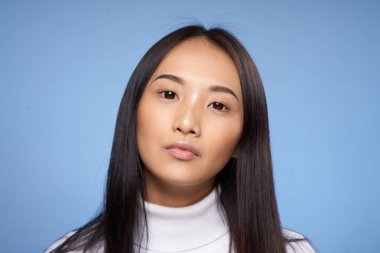 Asyalı kadın görünümlü beyaz kazak mavi arka planda kırpılmış