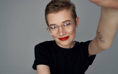 Kısa saçlı, kırmızı dudaklı, siyah tişörtlü, gülümseyen güzel bir kadın.