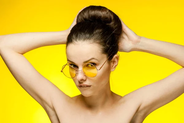Женщина с голыми плечами желтые очки руки около лица чистая кожа — стоковое фото