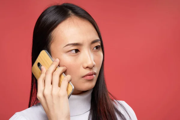 Симпатичная брюнетка разговаривает по телефону крупным планом на красном фоне — стоковое фото