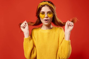 Sarı kazaklı güzel bir kadın saçlarını tutarken kırmızı arkaplanı kırpıyordu.