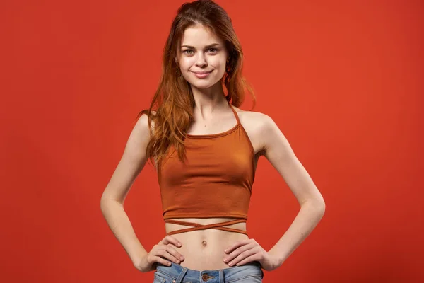 Vrolijke vrouw in rood t-shirt en jeans glamour studio rode achtergrond — Stockfoto