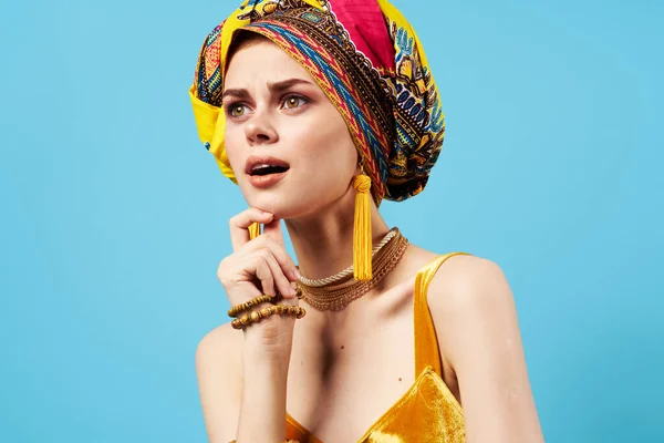 Glad känslomässig kvinna flerfärgad turban gul klänning dekoration blå bakgrund studio — Stockfoto