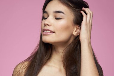 Güzel esmer, çıplak omuzlar, açık pembe arka plan.