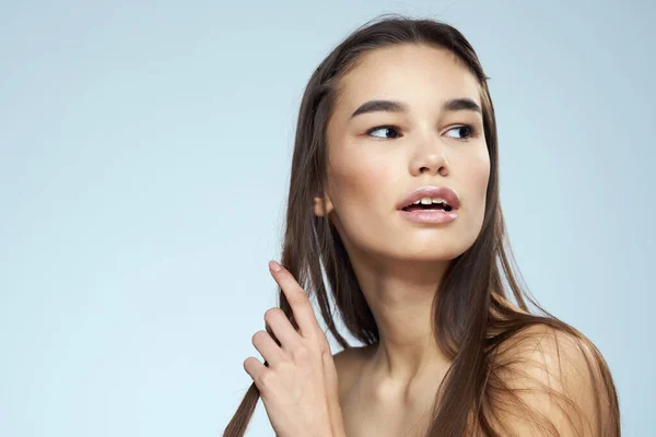 Morena bonita com ombros desnudados cabelos longos cuidados com o corpo fundo azul — Fotografia de Stock