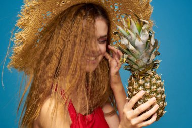 Elinde ananas olan hasır şapkalı bir kadın mı yoksa egzotik, eğlenceli bir meyve arka planı mı?