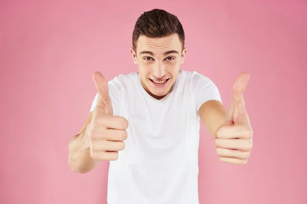 A man in a white t-shirt gestures with his hands emotions pink background studio cropped view — Stock Photo, Image