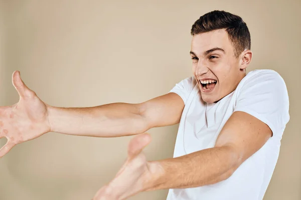 Emozionale uomo bianco t-shirt gesti con le mani stile di vita sfondo beige — Foto Stock
