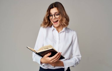 Elinde not defteri, yüzünde gözlüğü olan bir iş kadını.