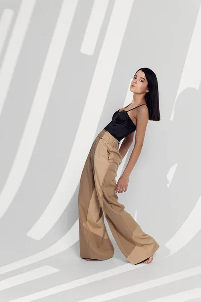 Vrouw model in broek poseren binnen met een vallende schaduw — Stockfoto