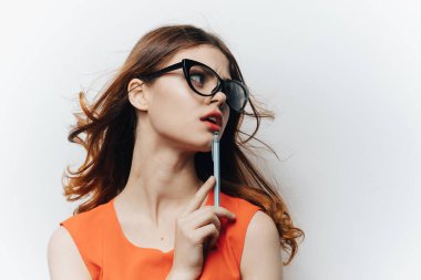 Güneş gözlüğü takmış, beyaz arka plan ve elinde kalem olan bir kız öğrenci.