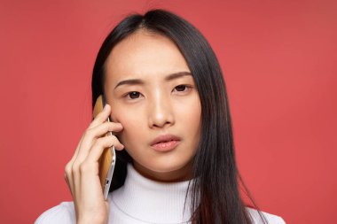 Güzel esmer, telefon teknolojisiyle konuşuyor. Yakın plan kırmızı arka plan.