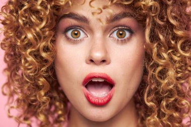 Seksi model, kıvırcık saçlı, yakından çekilmiş, ağzı açık bir cazibe. 