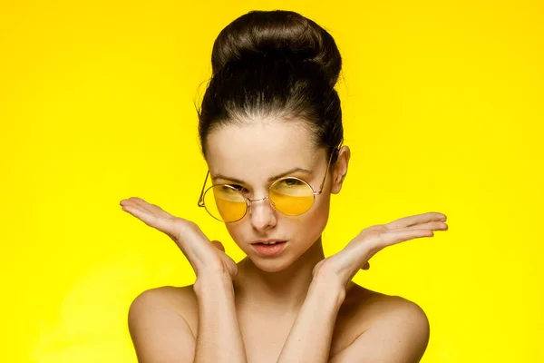 Ελκυστική γυναίκα με γυμνούς ώμους φορώντας γυαλιά συγκεντρώθηκαν μαλλιά χαμόγελο κίτρινο φόντο — Φωτογραφία Αρχείου