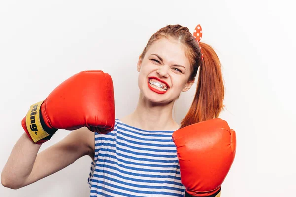 Femme forte en gants de boxe rouges et dans un t-shirt rayé vue de face arrière-plan clair — Photo