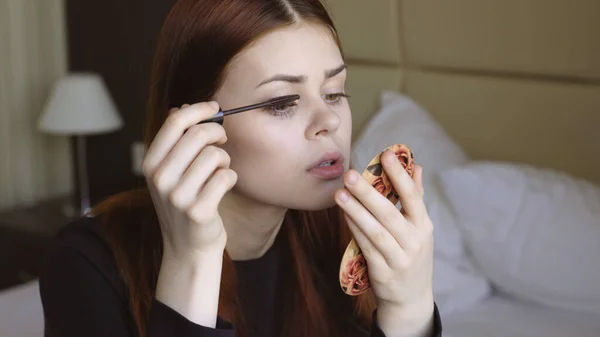 Vrouw in de slaapkamer van toepassing make-up op gezicht wimpers persoonlijke verzorging — Stockfoto