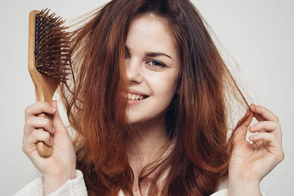 Happy woman with hairbrush on light background and healthy hair — Stock Photo, Image