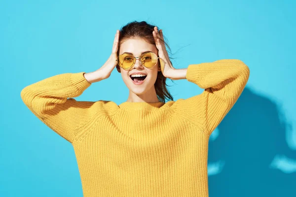 노란 스웨터를 입은 명랑 한 여인은 재미있게 파란 배경을 볼 수있다 — 스톡 사진