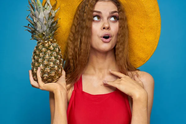 Frau mit gelbem Hut mit Ananas in den Händen Emotionen Spaß Lifestyle Sommer Obst blauer Hintergrund — Stockfoto