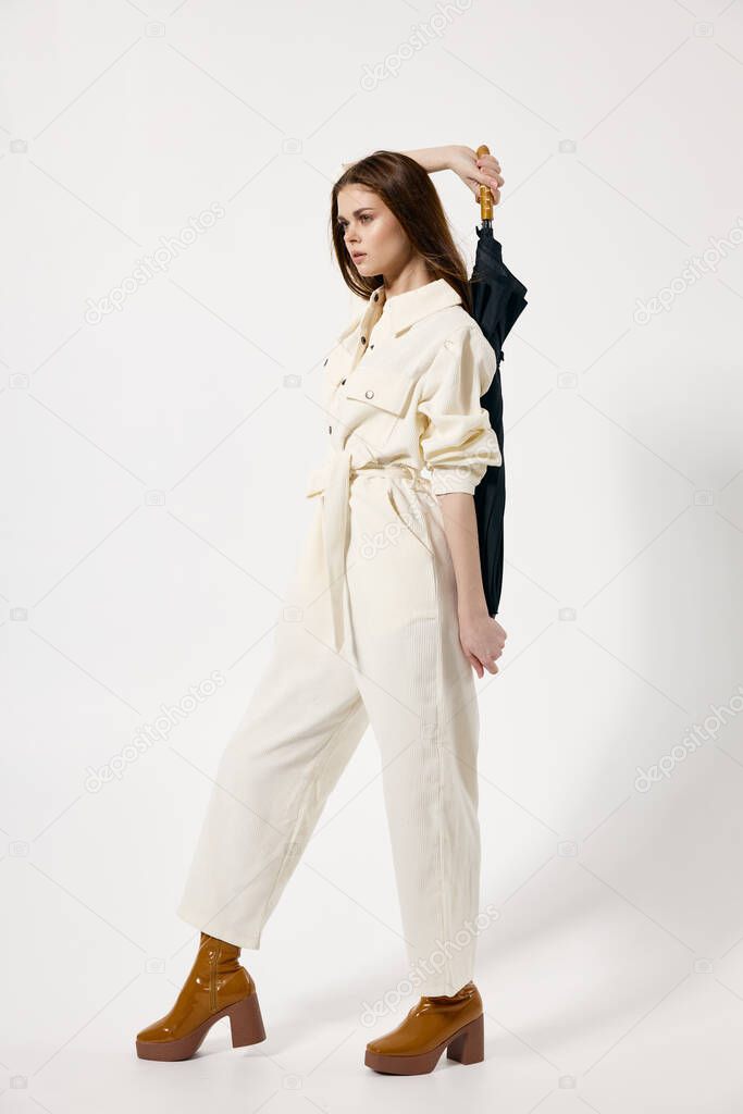 Woman in a White jumpsuit umbrella in her hands in full growth