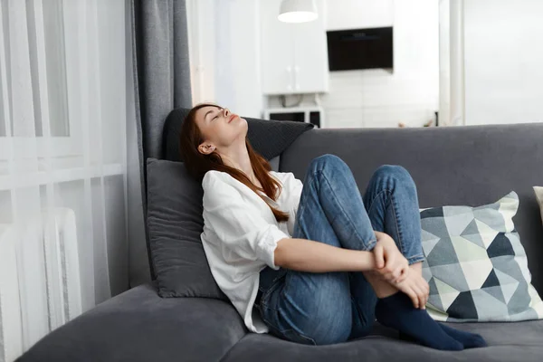 Mujer con los ojos cerrados sentado en el sofá tiró hacia atrás su cabeza en casa conveniencia —  Fotos de Stock