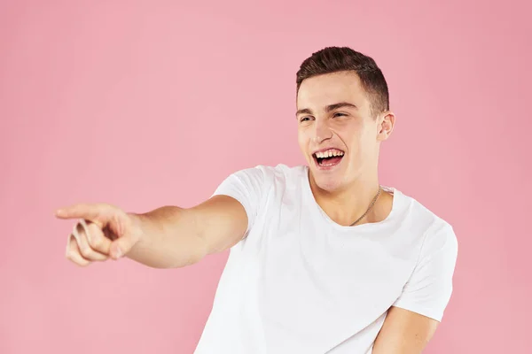 Uomo emotivo gesticolando con le mani bianco t-shirt rosa sfondo isolato — Foto Stock