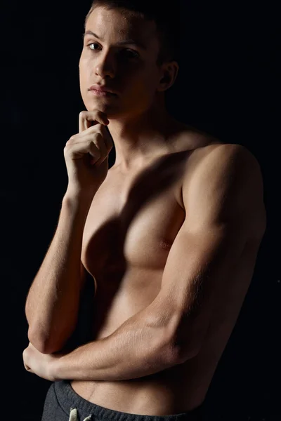 Jovem atleta com músculos bombeados dos braços em um fundo preto corte vista retrato — Fotografia de Stock