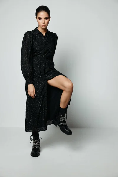Morena bonita maquiagem brilhante vestido preto perna dobrada no joelho moda — Fotografia de Stock