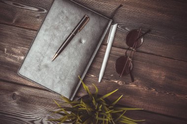 Not defteri bardakları ve saksıda bir çiçek Tahta bir masanın üstünde kalem ofisi