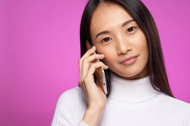 Neşeli, güzel esmer telefonda konuşuyor, pembe manzaralı arka plan.