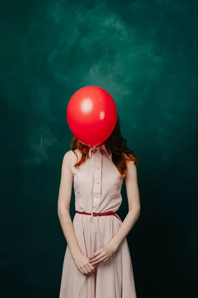 Mujer con bola roja en frente de la cara sobre fondo verde en vestido rosa vista recortada — Foto de Stock