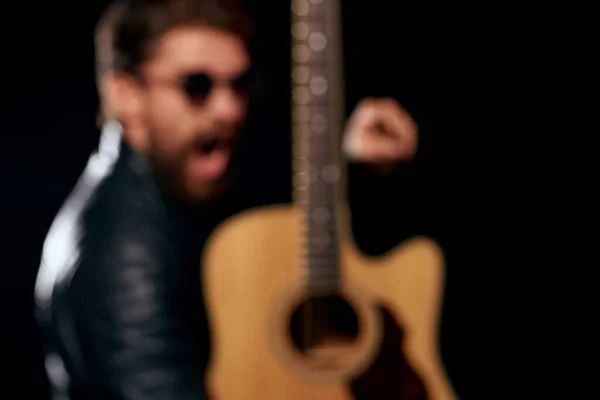 En man med en gitarr i händerna läder jacka musik prestanda rockstjärna modern stil mörk bakgrund — Stockfoto