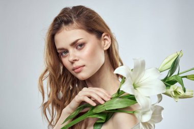 Çiçeklerle süslenmiş kız portresi. Kapalı yay, çıplak omuzlar. Makyaj.