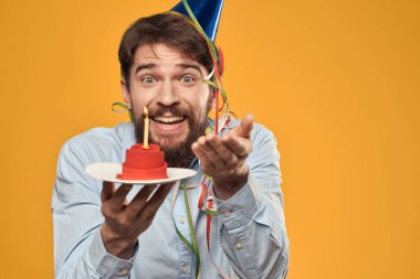 Elinde doğum günü pastası ve mumuyla şapkalı bir çocuk.