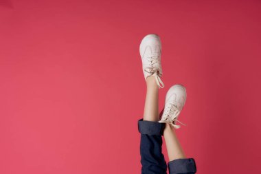 Ters dönmüş kadın bacakları beyaz spor ayakkabılar, sokak tarzı pembe arka plan.