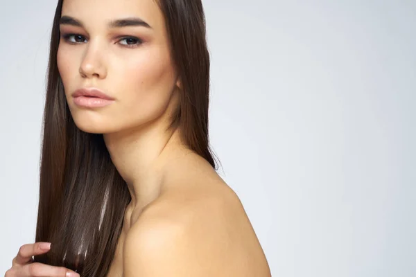 Mooie brunette naakt schouders lang haar close-up licht achtergrond — Stockfoto