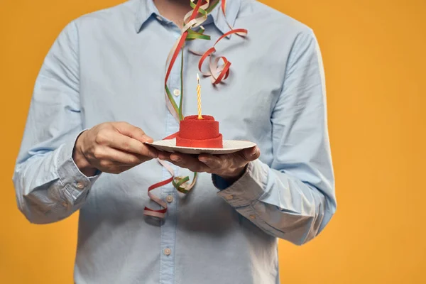 Un uomo che tiene una torta in un piatto e una candela da sfondo isolato — Foto Stock