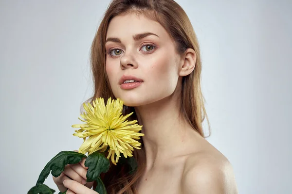 Urocza pani z żółtym kwiatem na jasnym tle przycięty widok — Zdjęcie stockowe