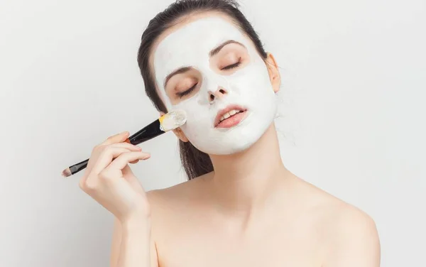 Femme aux épaules nues appliquant une brosse de maquillage sur le visage — Photo