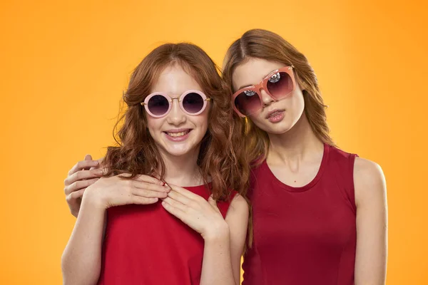 Alegre mamá e hija usando gafas de sol estilo de vida amistad familia amarillo fondo estudio — Foto de Stock