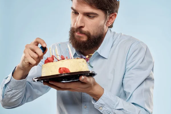 Homem de aniversário mulher em chapéus de festa em um fundo azul e bolo com velas — Fotografia de Stock