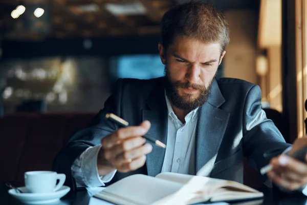 Un uomo si siede in un caffè a un tavolo Tazza di documenti di lavoro caffè — Foto Stock