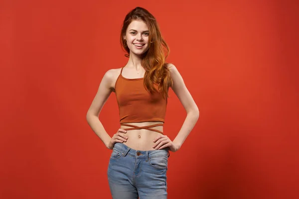 Mooie vrouw in rood t shirt en jeans straat mode aantrekkelijk look rood achtergrond — Stockfoto