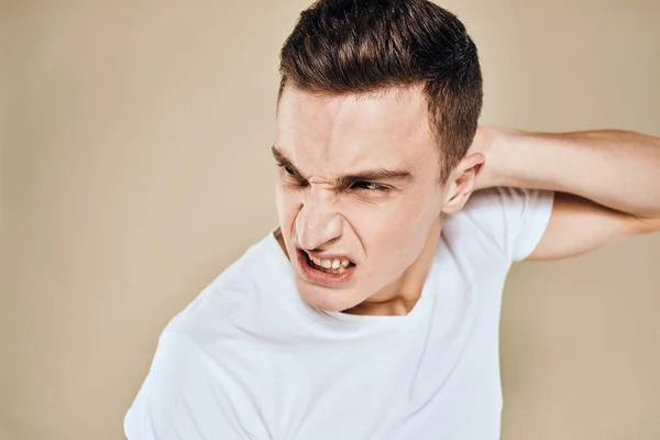 Homme avec expression faciale mécontente émotions blanc t-shirt gestes avec les mains fond beige — Photo