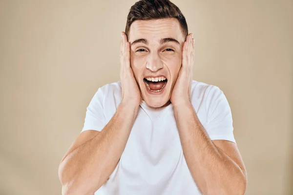 Emotional man white t-shirt gestures with hands lifestyle beige background — Stock Photo, Image